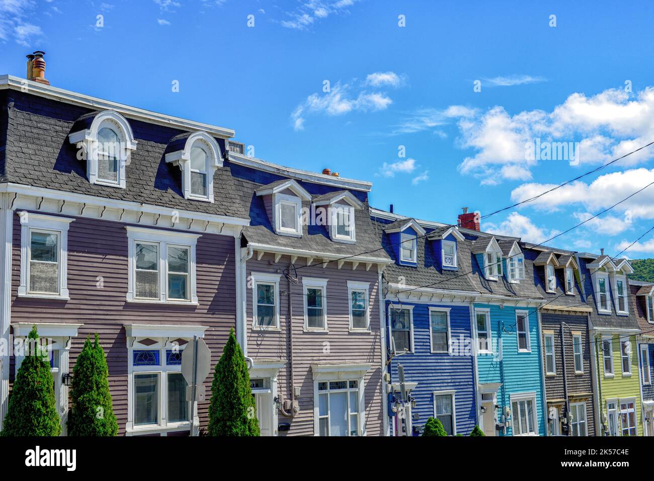 Multiple colorful wooden historic residential Second Empire style buildings attached with mansard roofs and arched and curved dormers on Cochrane St Stock Photo