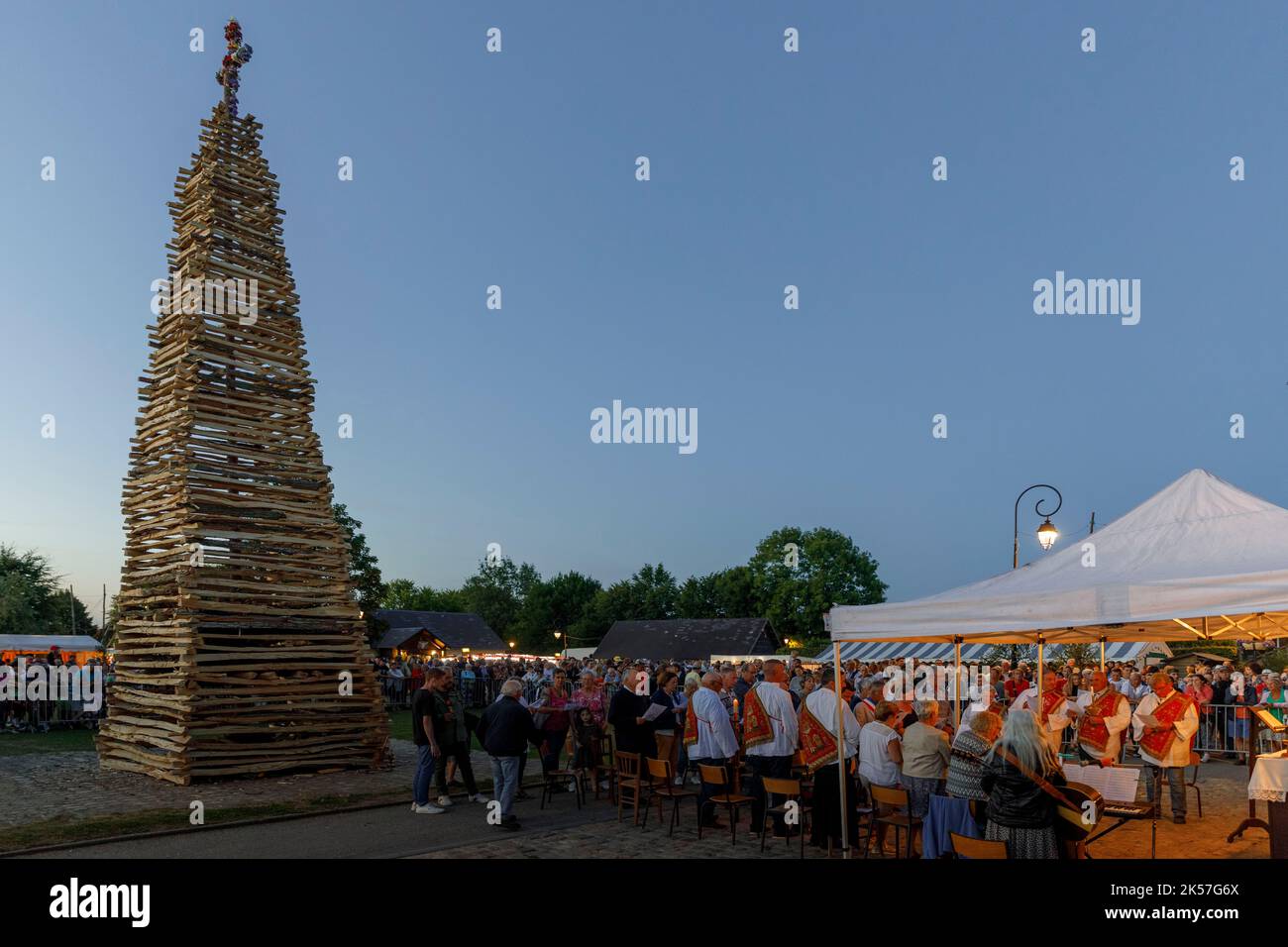 France, Eure, La Haye-de-Routot, traditional bonfire of Saint-Clair, a 15 meters high pyramid of dry wood is erected, on the village square, in front of the church and its thousand-year-old yews. A mass and a blessing precede the burning of the stake, if the cross at the top does not burn, it is a good sign for the 12 months to come, bringing back home a piece of charred wood, called brandon, will protect the house against lightning Stock Photo