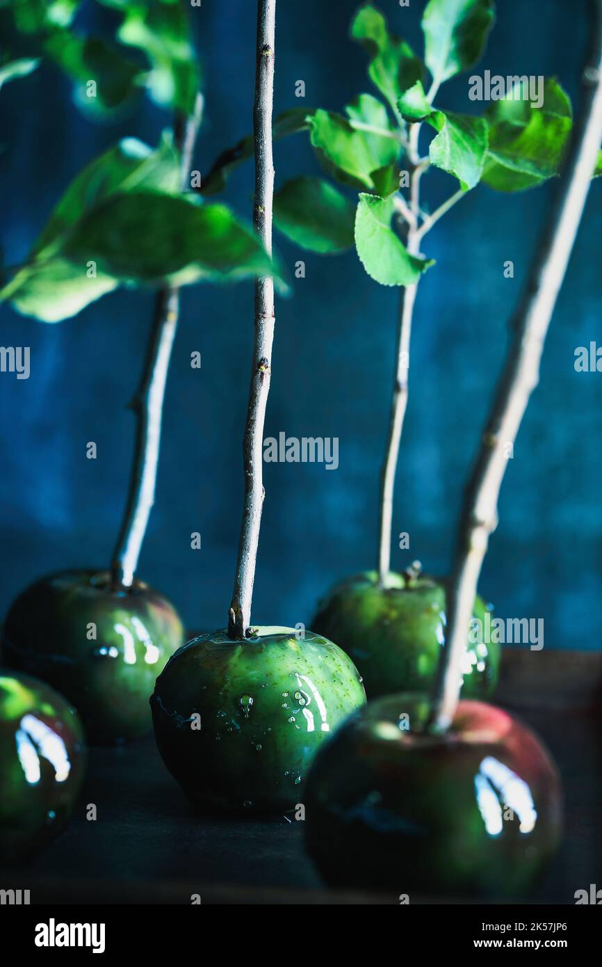 Poisoned green candied apples for Halloween. Selective focus on center apple with blurred foreground and background. Stock Photo