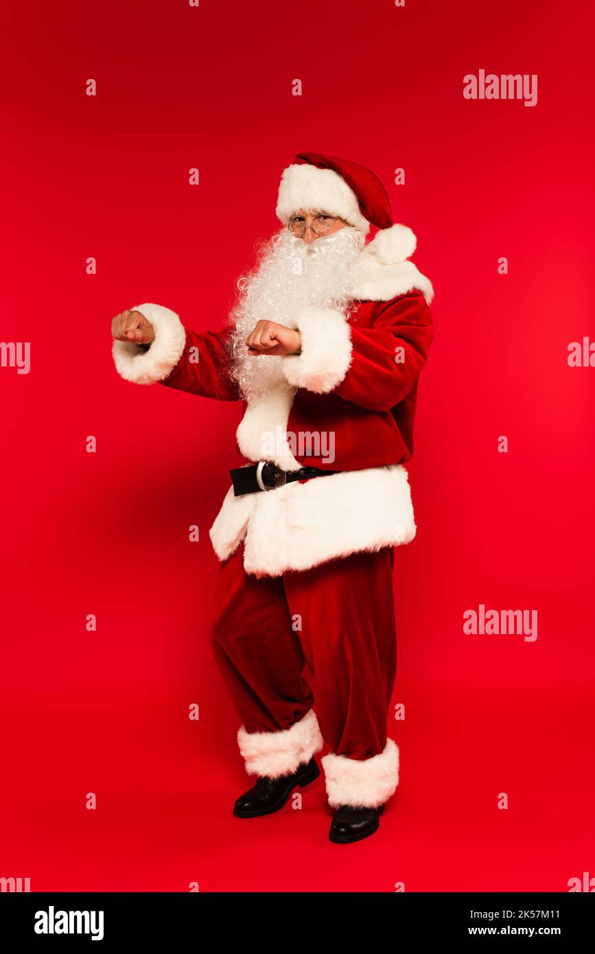 Bearded santa claus looking at camera while dancing on red background,stock image Stock Photo