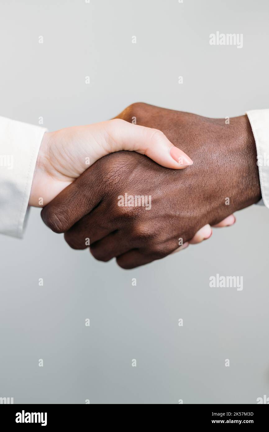 Diverse handshake. Gender equality. International partnership. Deal agreement. Closeup of multiracial business people shaking hands isolated on neutra Stock Photo