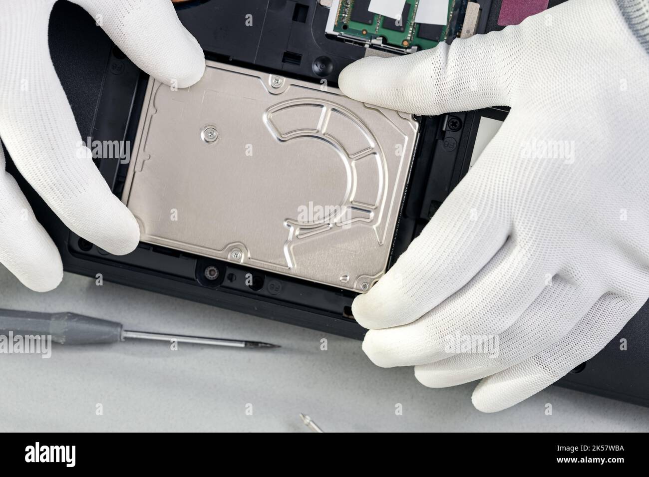 Technician hands removing an old mechanical hard disk from a laptop. Top view Stock Photo