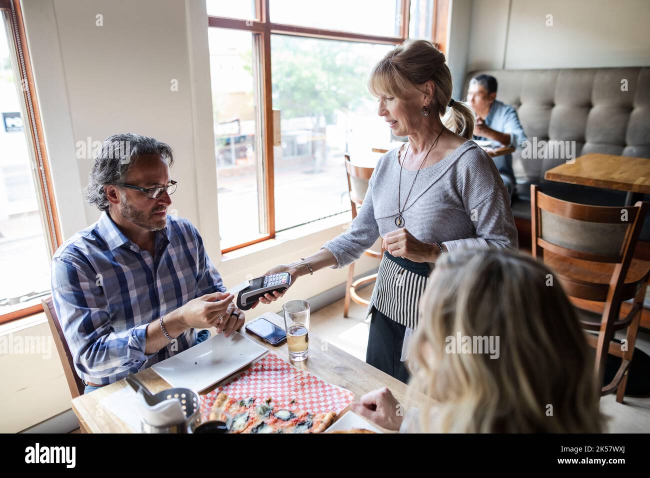 Customer paying waitress with smart card in restaurant Stock Photo