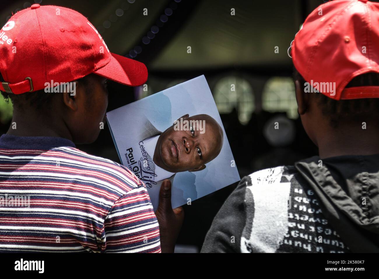 A mourner holds an order of service with a portrait of Paul Gicheru