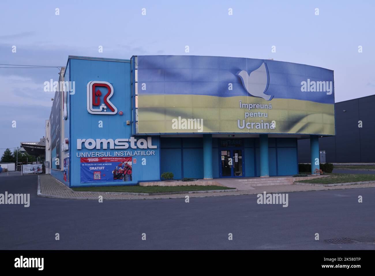 Building with large banner with image of blue-yellow Ukrainian flag on its facade and a dove of peace with the Romanian text 'Impreuna pentru Ucraina' Stock Photo