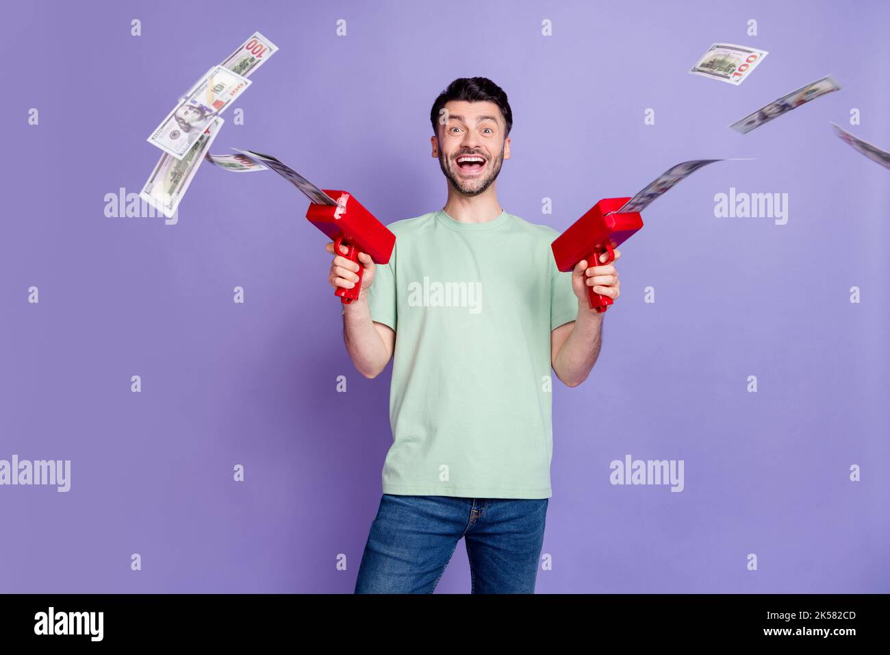 Photo portrait of attractive young guy wasting money gun shooting lottery  wear trendy gray outfit isolated on violet color background Stock Photo -  Alamy