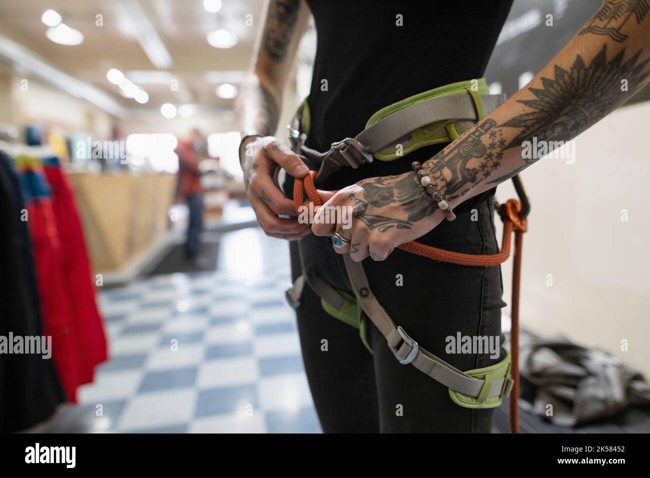 Young transgender woman preparing safety harness at climbing center Stock Photo
