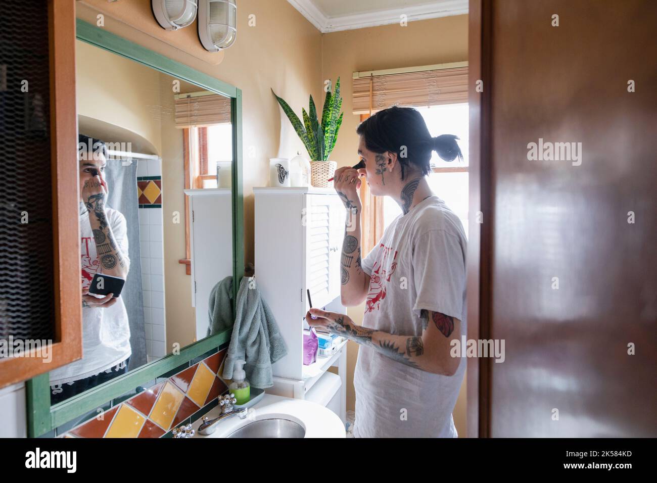 Young transgender woman applying makeup at bathroom mirror Stock Photo - Alamy
