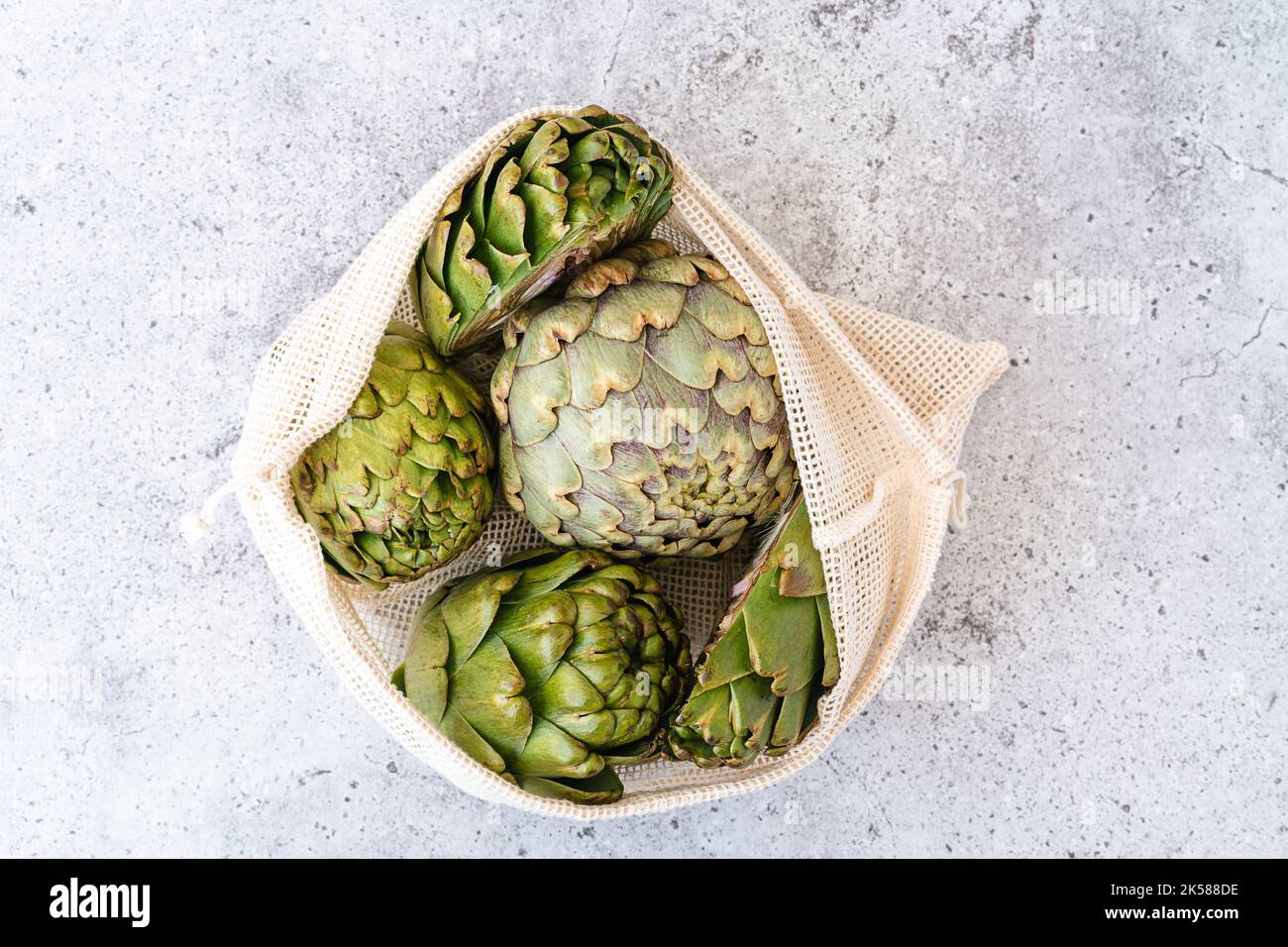 Top view of artichoke in linen eco bag on table. Flat lay of Healthy food vegetables. Stock Photo