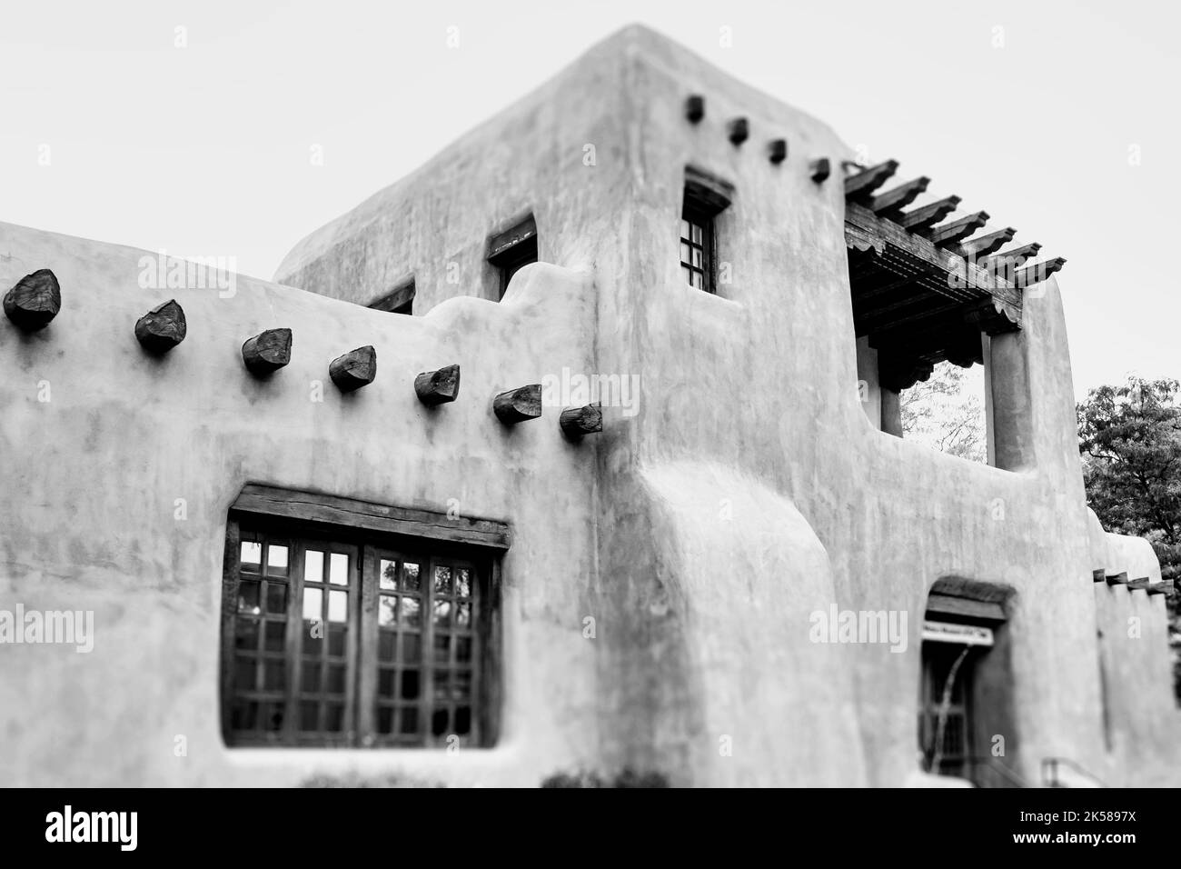 A black and white image of an adobe building with windows and wooden