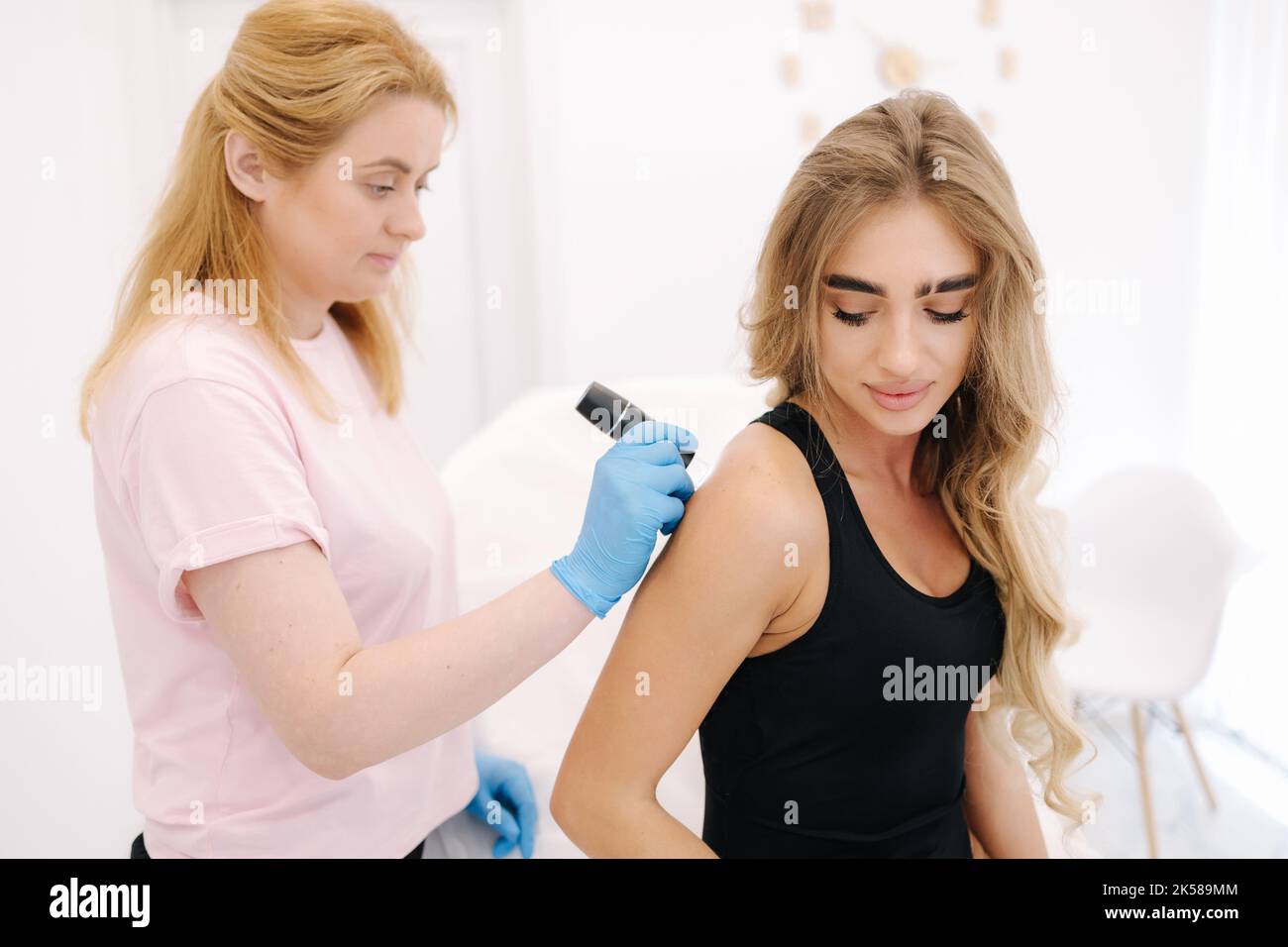 Female doctor dermatologist examines birthmarks and skin moles of the patient with a dermatoscope. Stock Photo