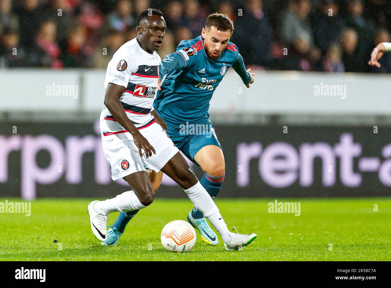 HERNING, DENMARK - OCTOBER 6: Pione Sisto of FC Midtjylland, Orkun Kokcu (c) of Feyenoord during the Group F - UEFA Europa League match between FC Midtjylland and Feyenoord at Messecenter Herning Arena on October 6, 2022 in Herning, Denmark (Photo by Anders Kjaerbye/Orange Pictures) Stock Photo