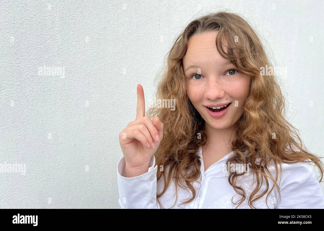 a girl on a white background in a white blouse, fair-haired, shows different cheerful emotions, she makes faces, she laughs happily, she ruffles her hair and shows her tongue. High quality photo Stock Photo