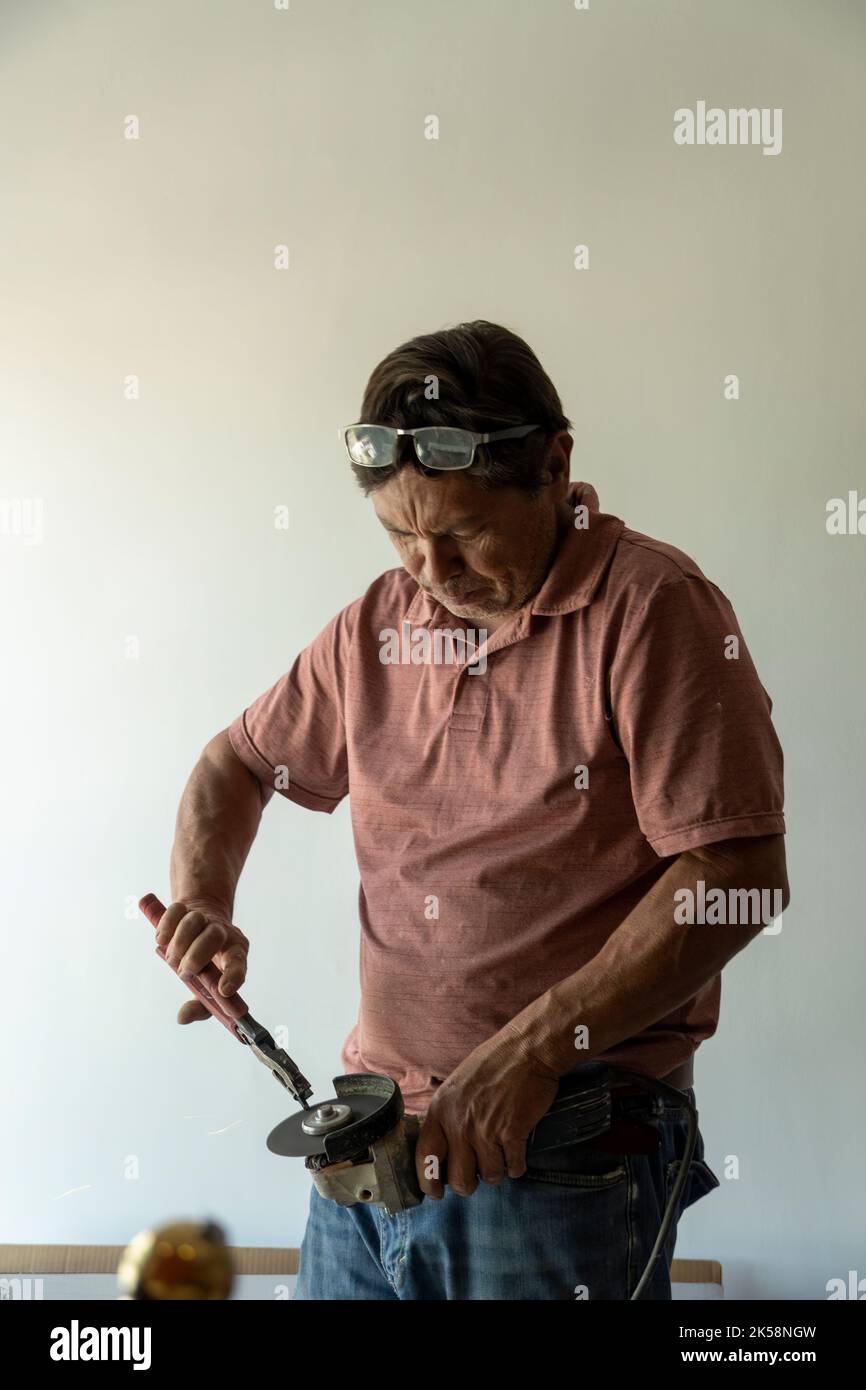 man using angle grinder, cutting a screw, friction sparks, clamping