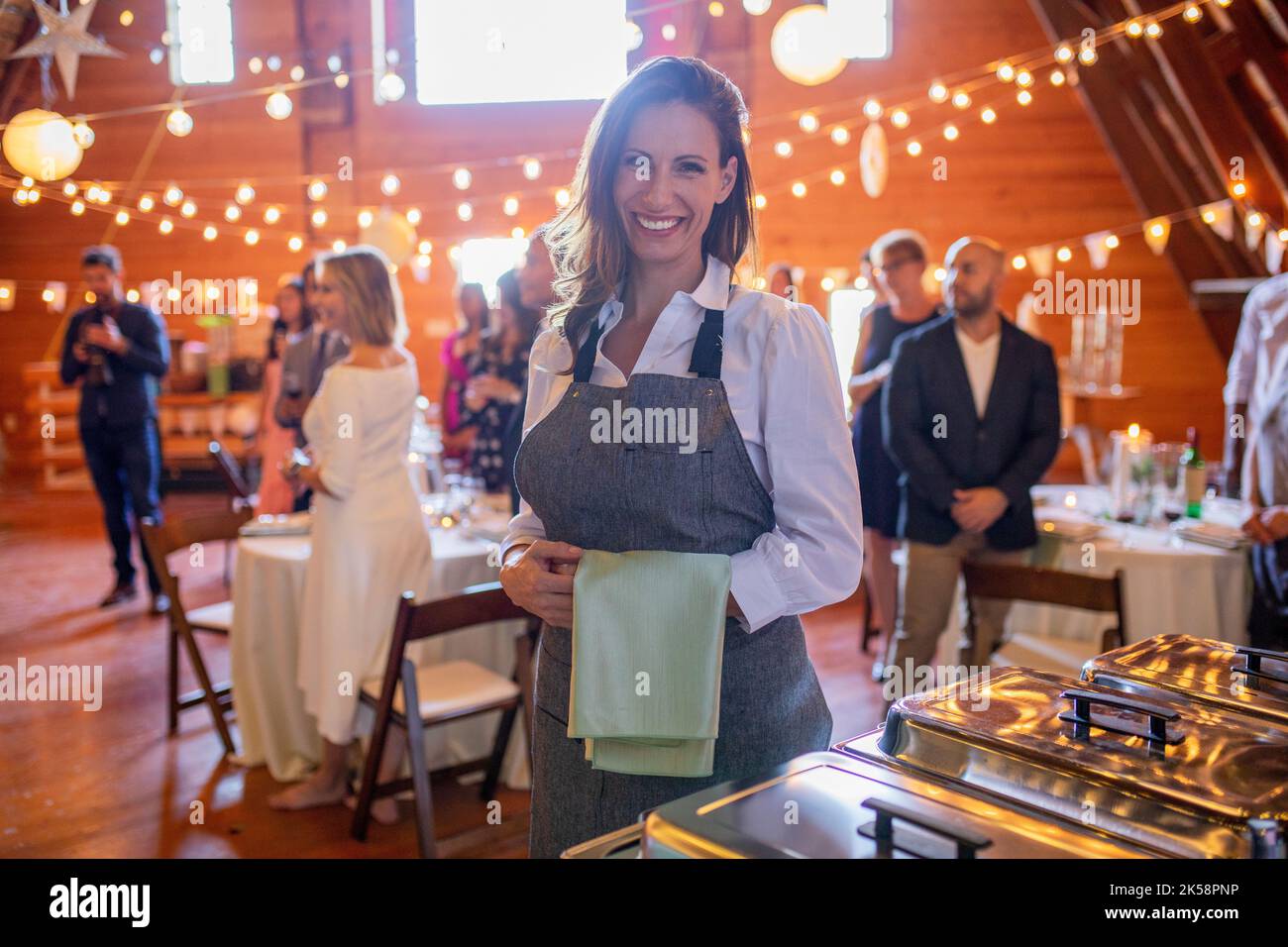 Smiling female server working at wedding reception hires stock