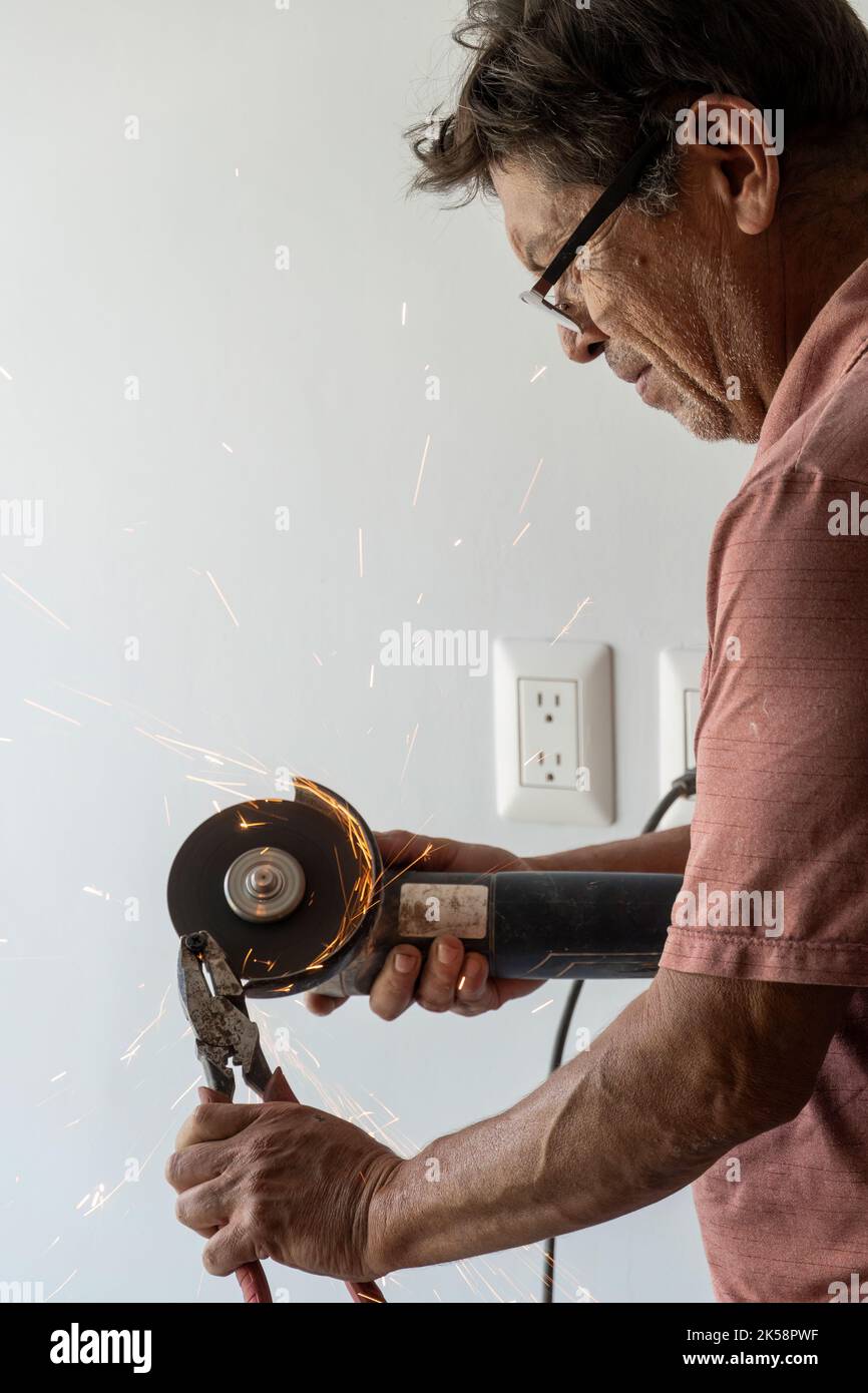 man using angle grinder, cutting a screw, friction sparks, clamping