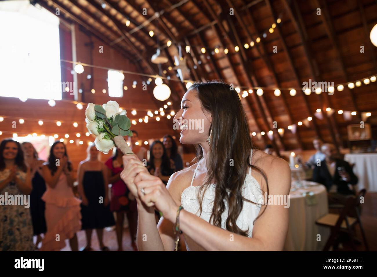 Happy bride preparing to throw flower bouquet at wedding reception