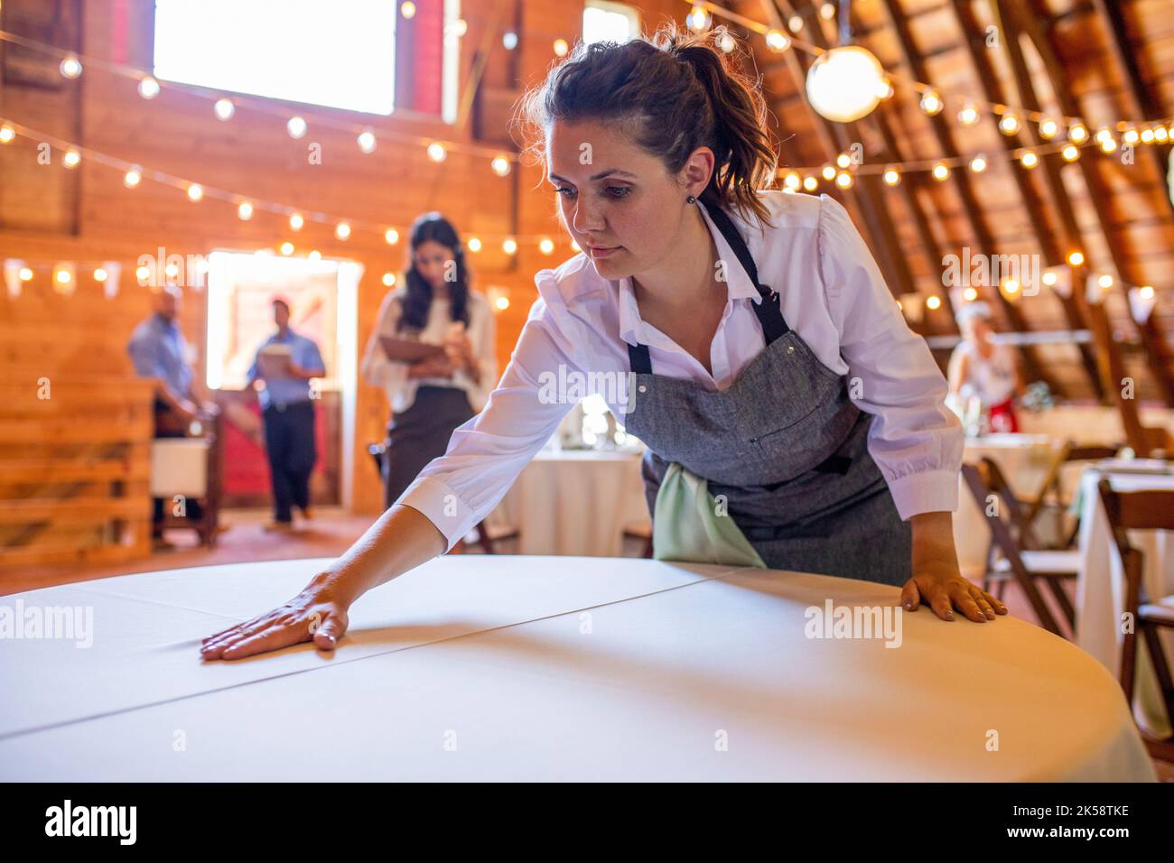 Dedicated female server smoothing tablecloth for wedding reception Stock Photo