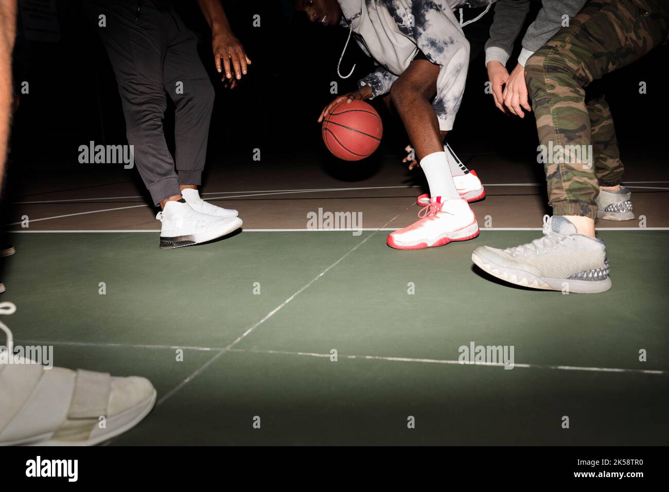 Basketball player bouncing ball on court at night Stock Photo Alamy