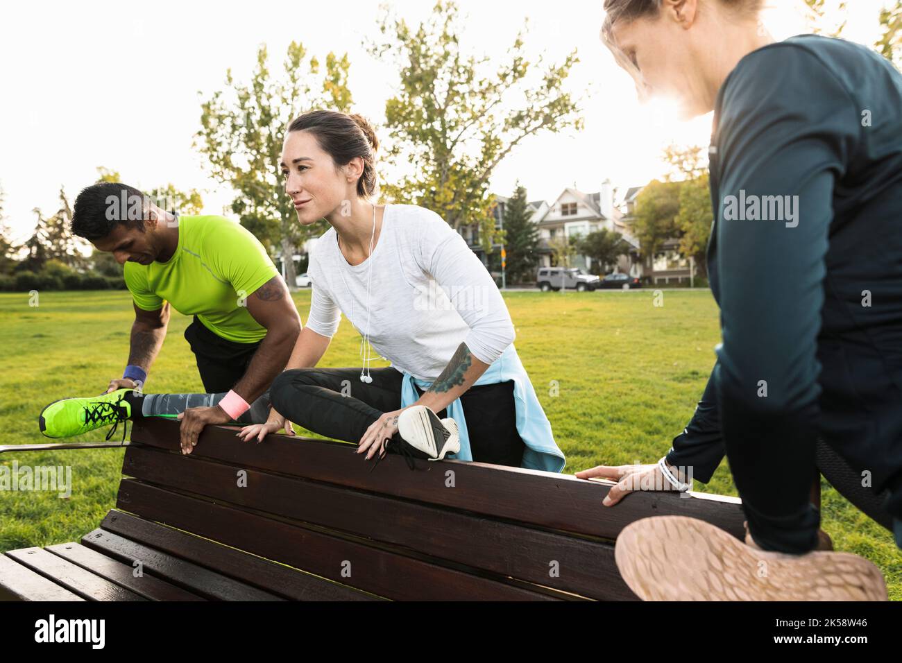 Three runners stretching on park bench Stock Photo Alamy