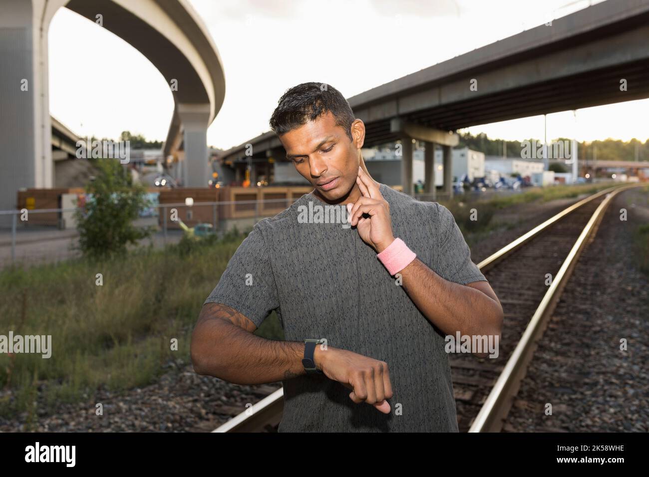Mid adult man checking pulse and looking at sports watch Stock Photo
