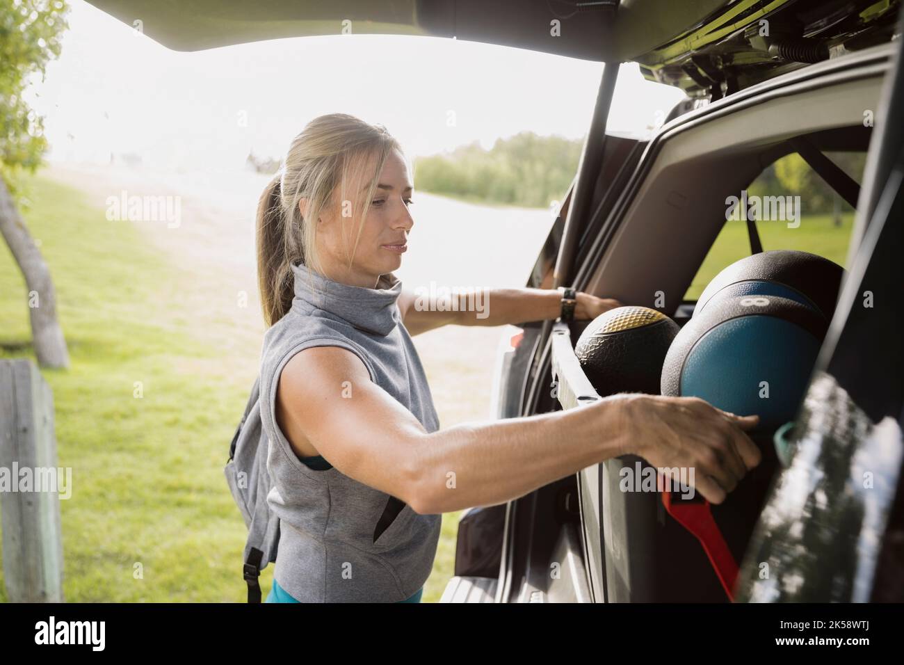 Personal trainer taking sports equipment out of car before bootcamp Stock Photo