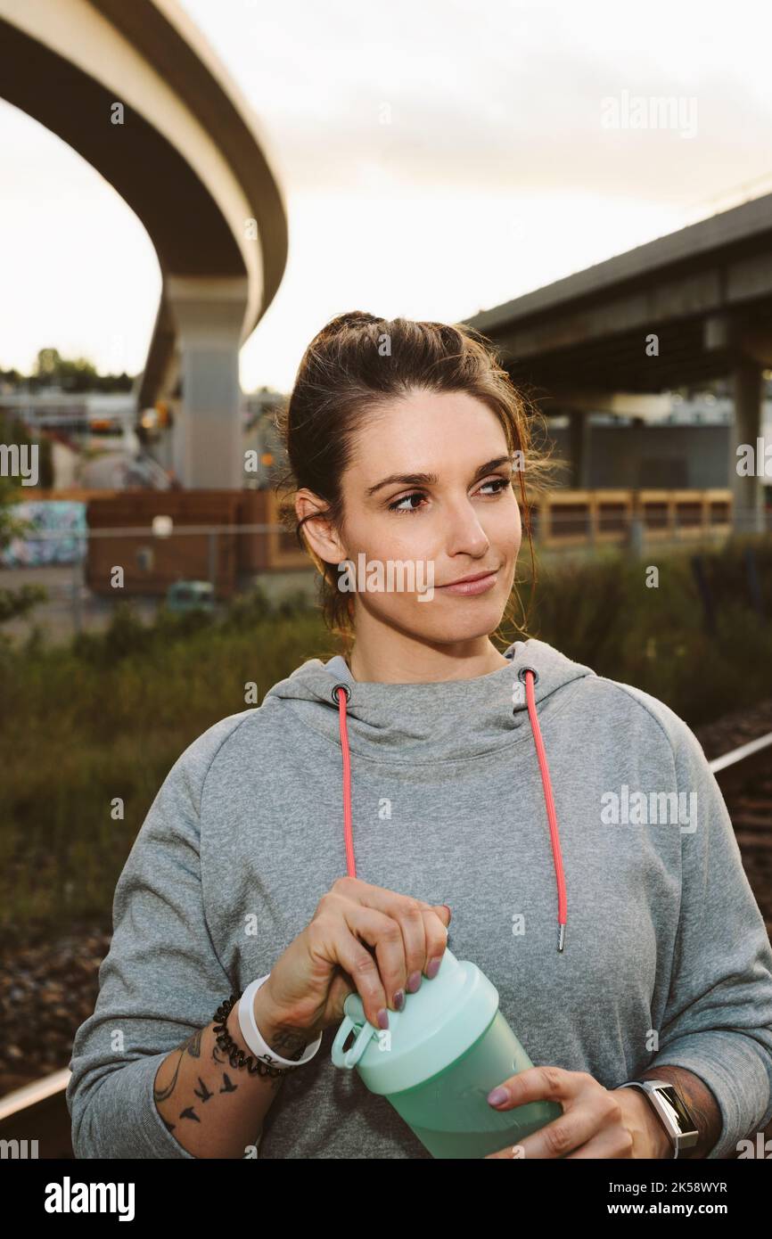 Portrait of mid adult woman smiling and looking sideways with sports bottle Stock Photo