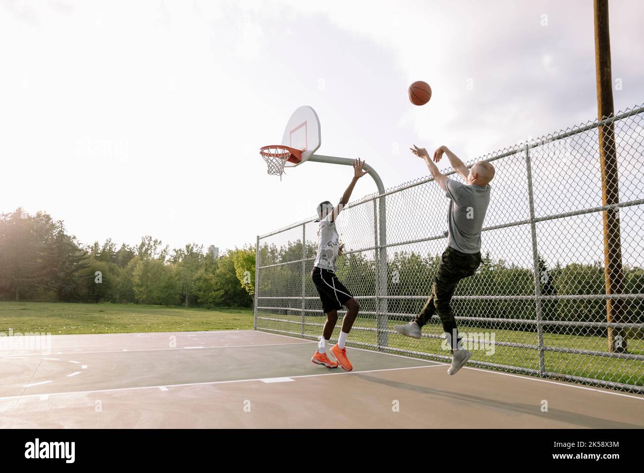 Basketball player aiming to score goal with opponent jumping to defend Stock Photo