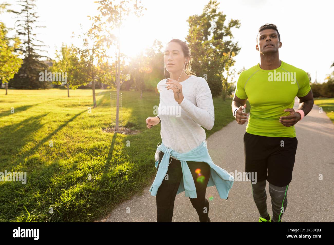 Two people running in park in sunlight Stock Photo