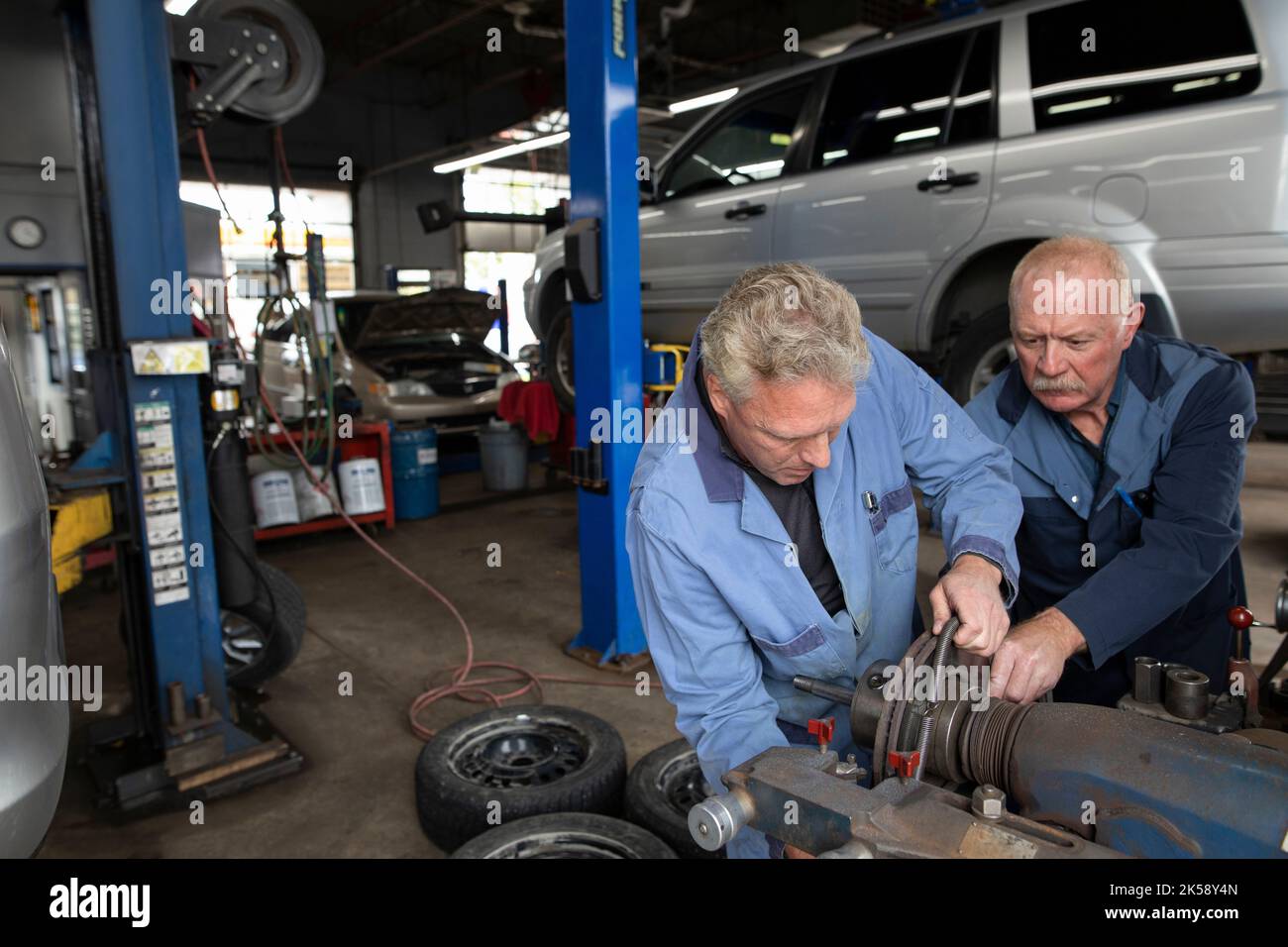 Two mechanics using machinery in automobile workshop Stock Photo