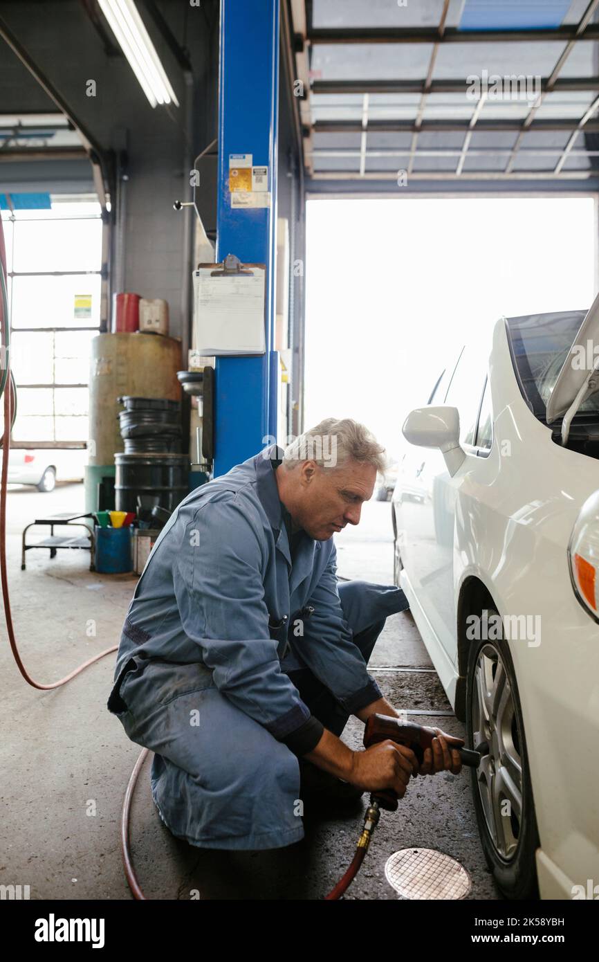 Mechanic changing tire on car in garage Stock Photo Alamy