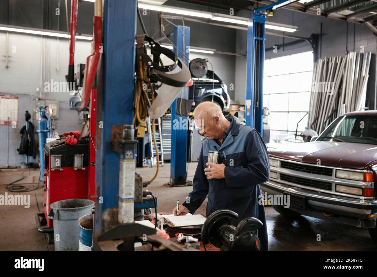 Mechanic wearing overalls holding coffee and writing in Stock Photo Alamy