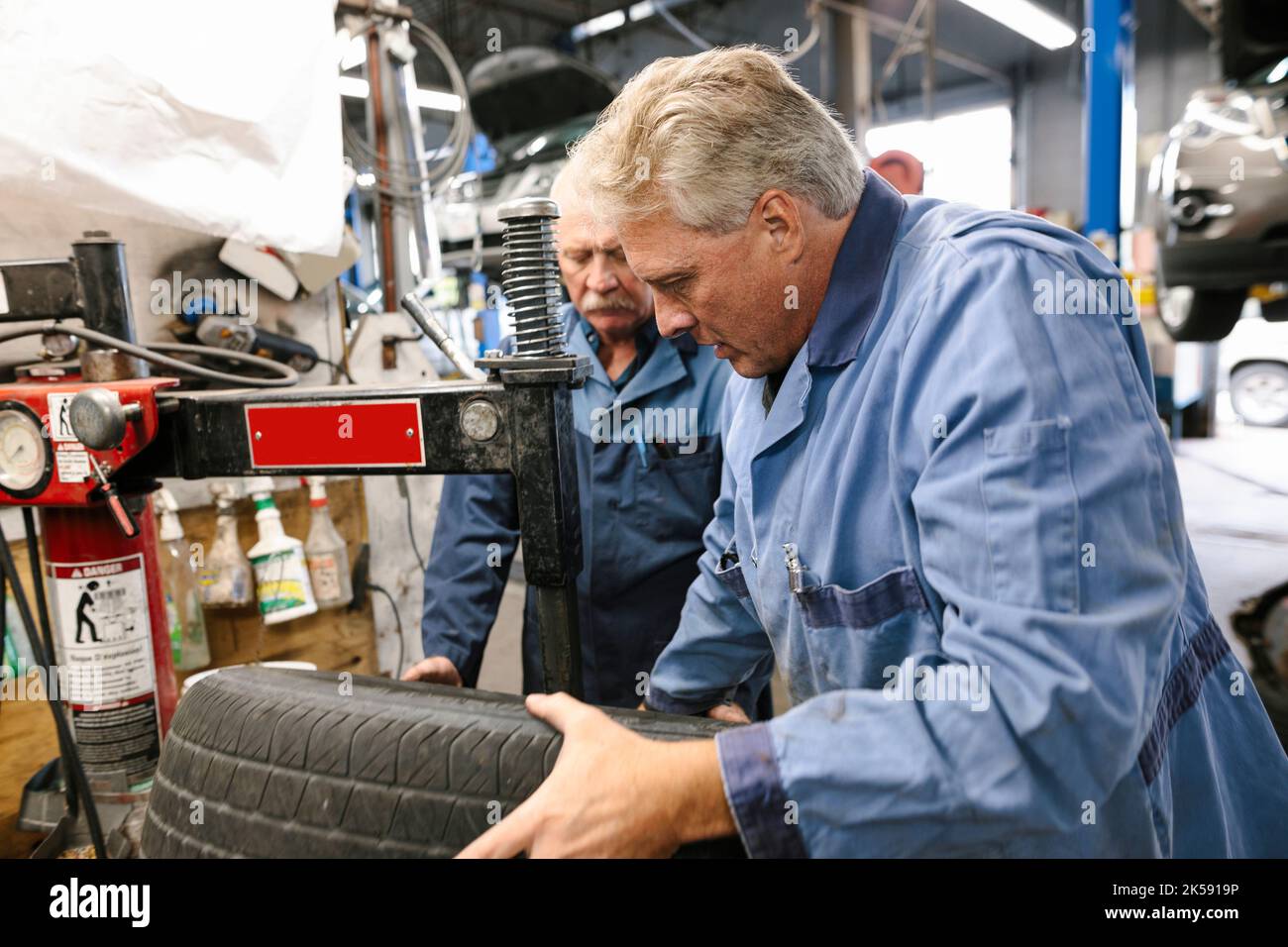 Mechanics repairing tire in automobile workshop Stock Photo