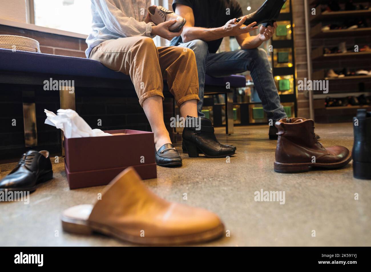 Woman sitting down and trying on shoes in shoe store Stock Photo