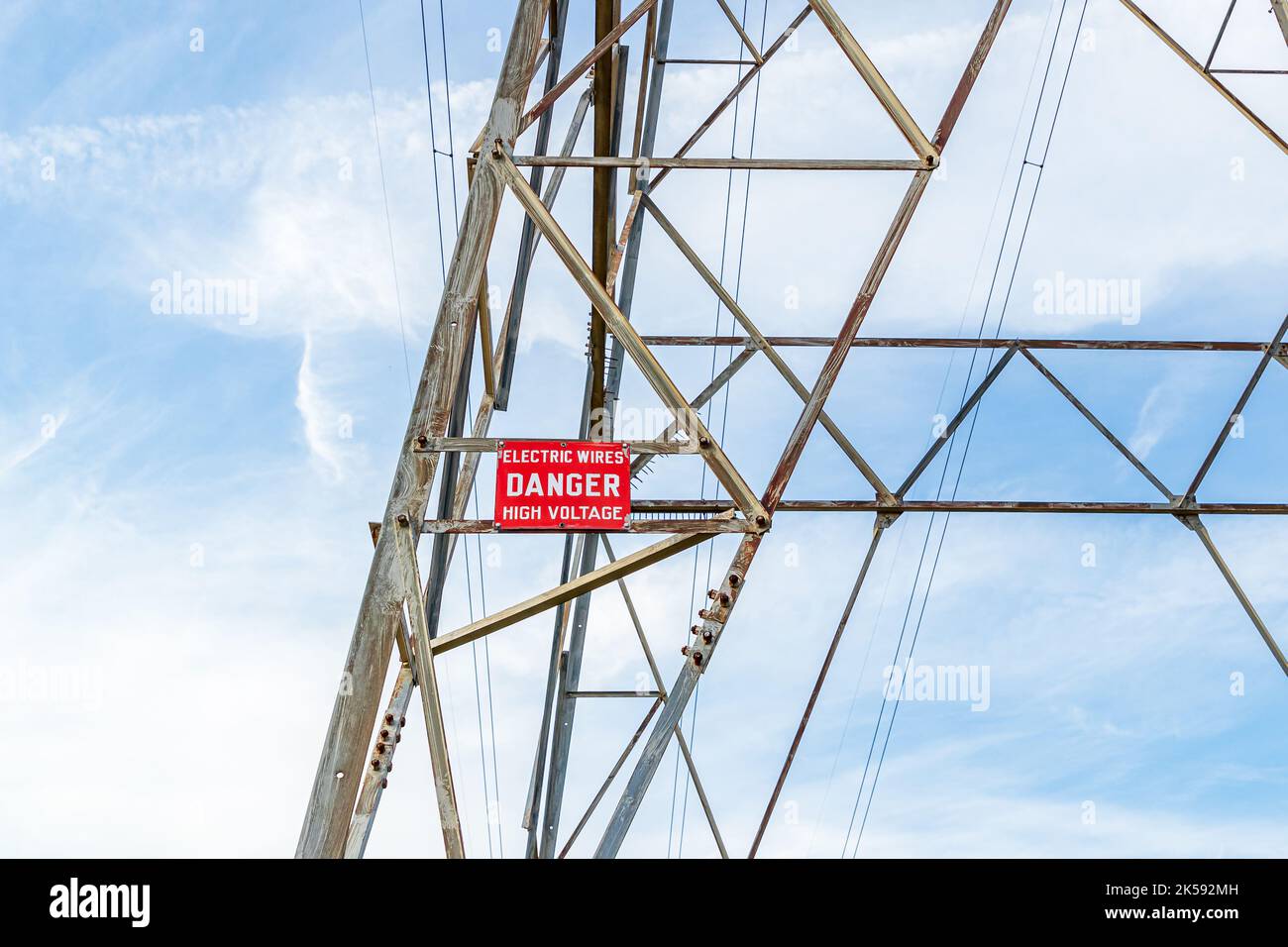 High voltage warning sign on electrical utility tower. Electricity, power lines, and electrical grid safety concept Stock Photo