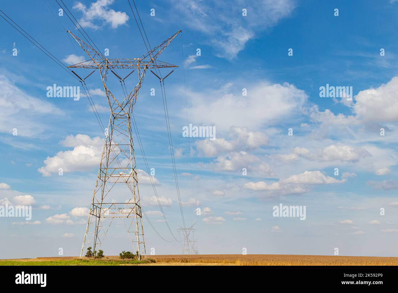 Electricity transmission towers in rural farm field. Electrical power grid and distribution safety, security and maintenance concept Stock Photo