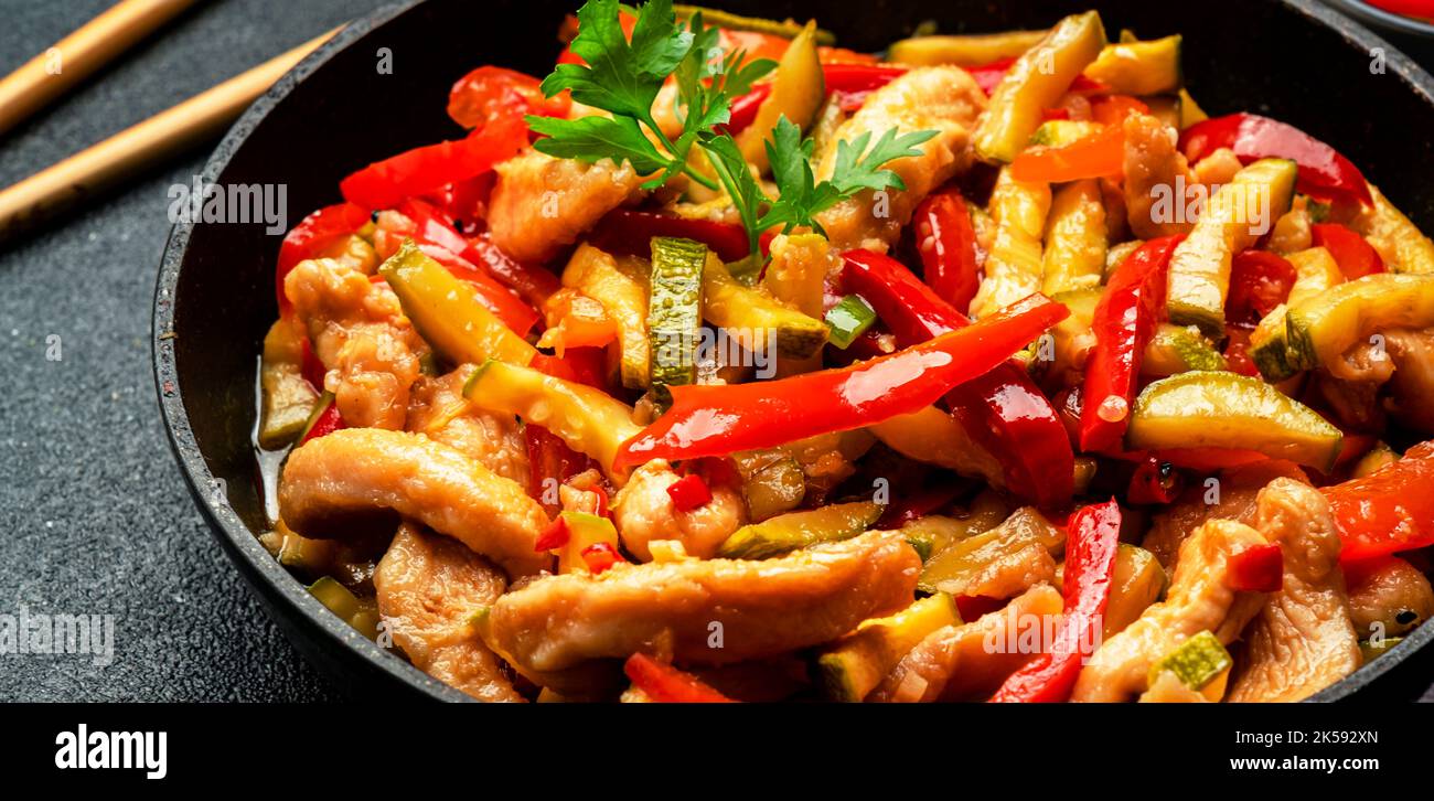 Asian cuisine, stir fry with chicken, red paprika pepper and zucchini