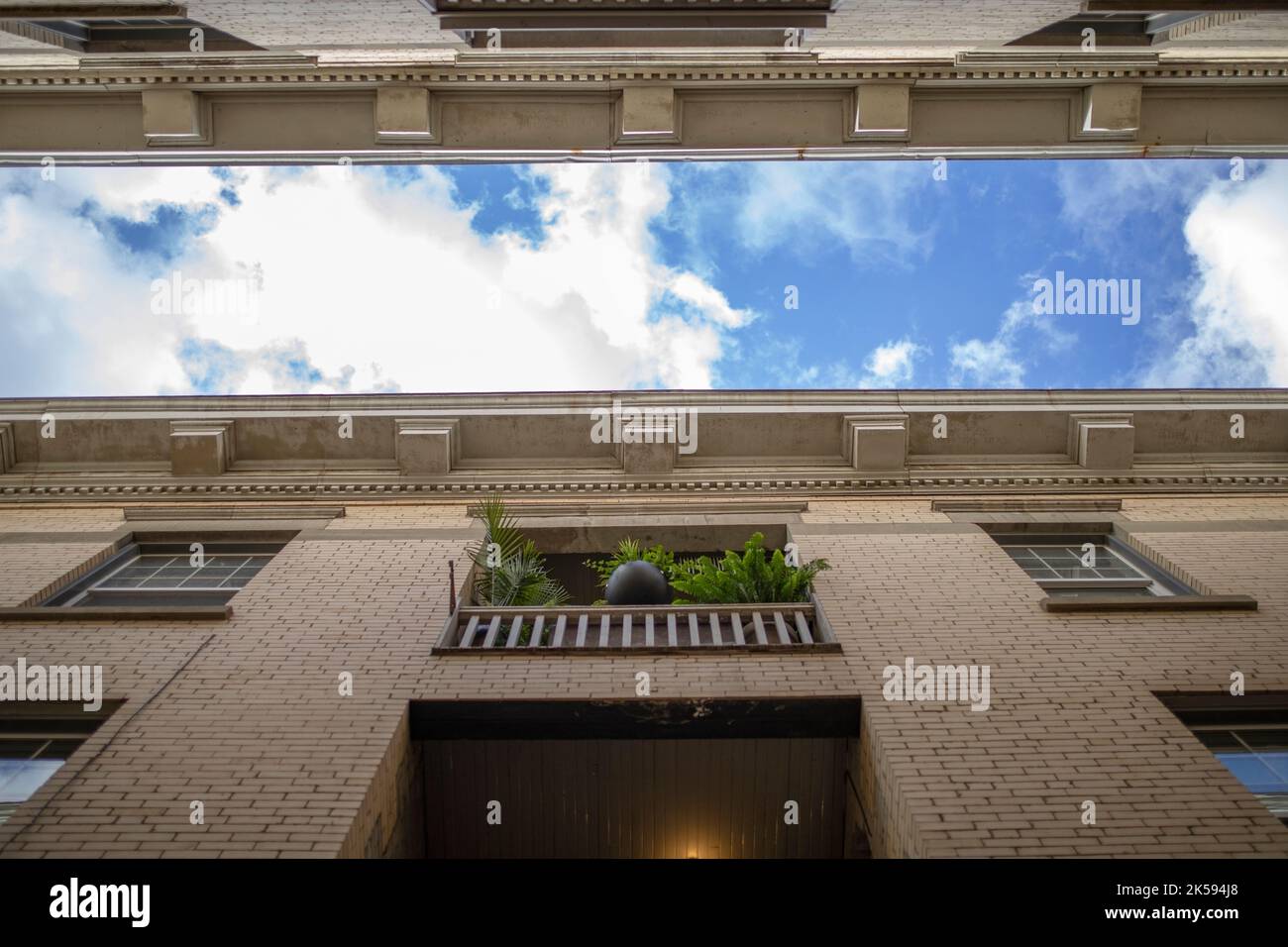 View from below blue sky and clouds between apartment building walls Stock Photo