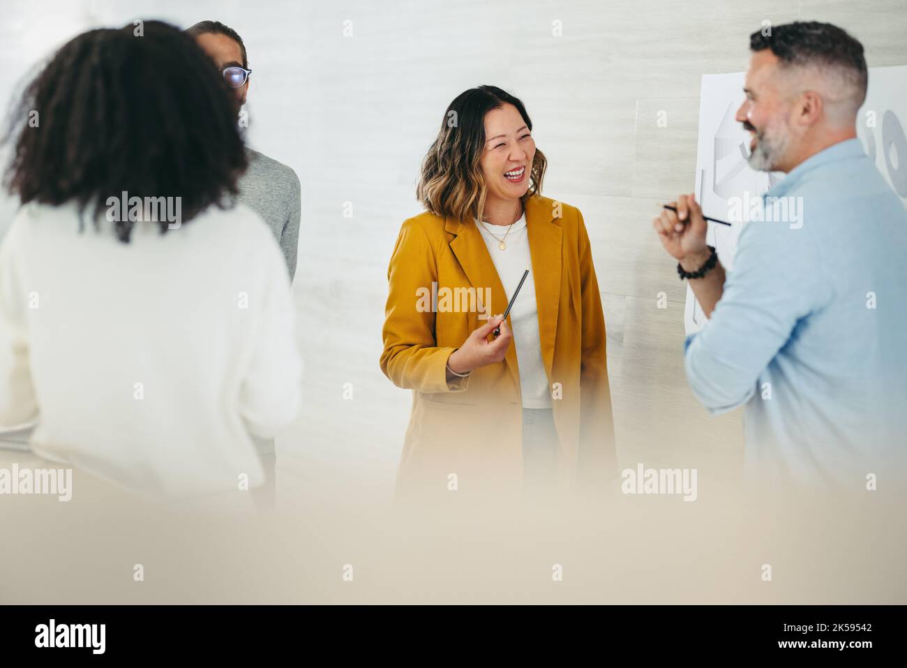 Happy businesspeople laughing cheerfully while having a discussion on a creative office. Group of multicultural design professionals collaborating on Stock Photo
