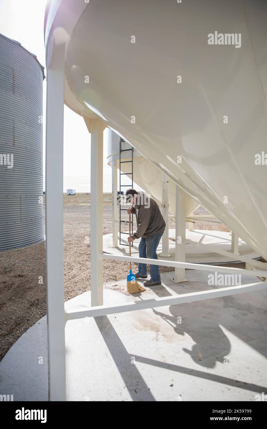 Male farmer sweeping below silos Stock Photo Alamy