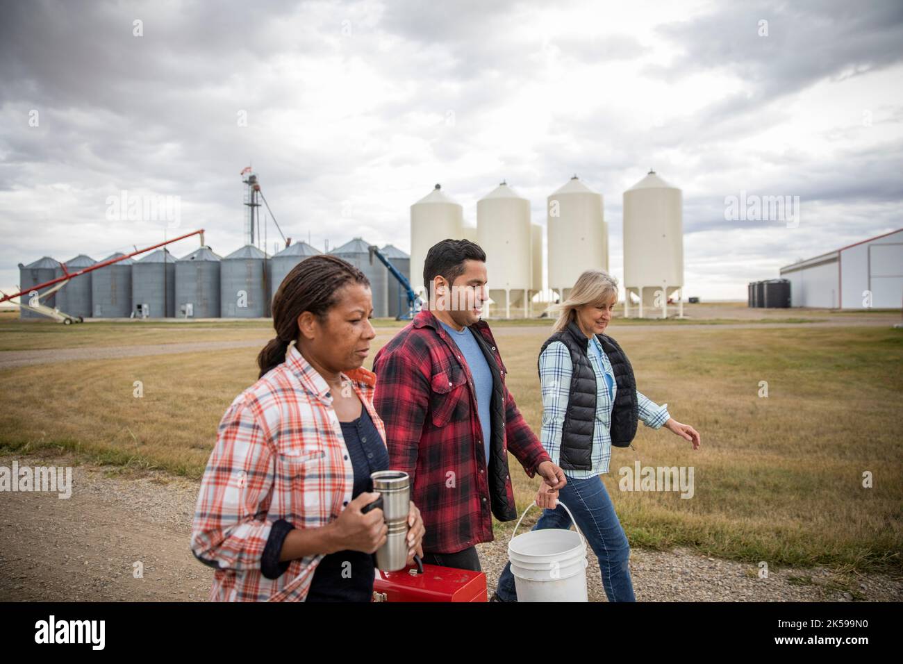 Farmers walking along silos on farm Stock Photo Alamy