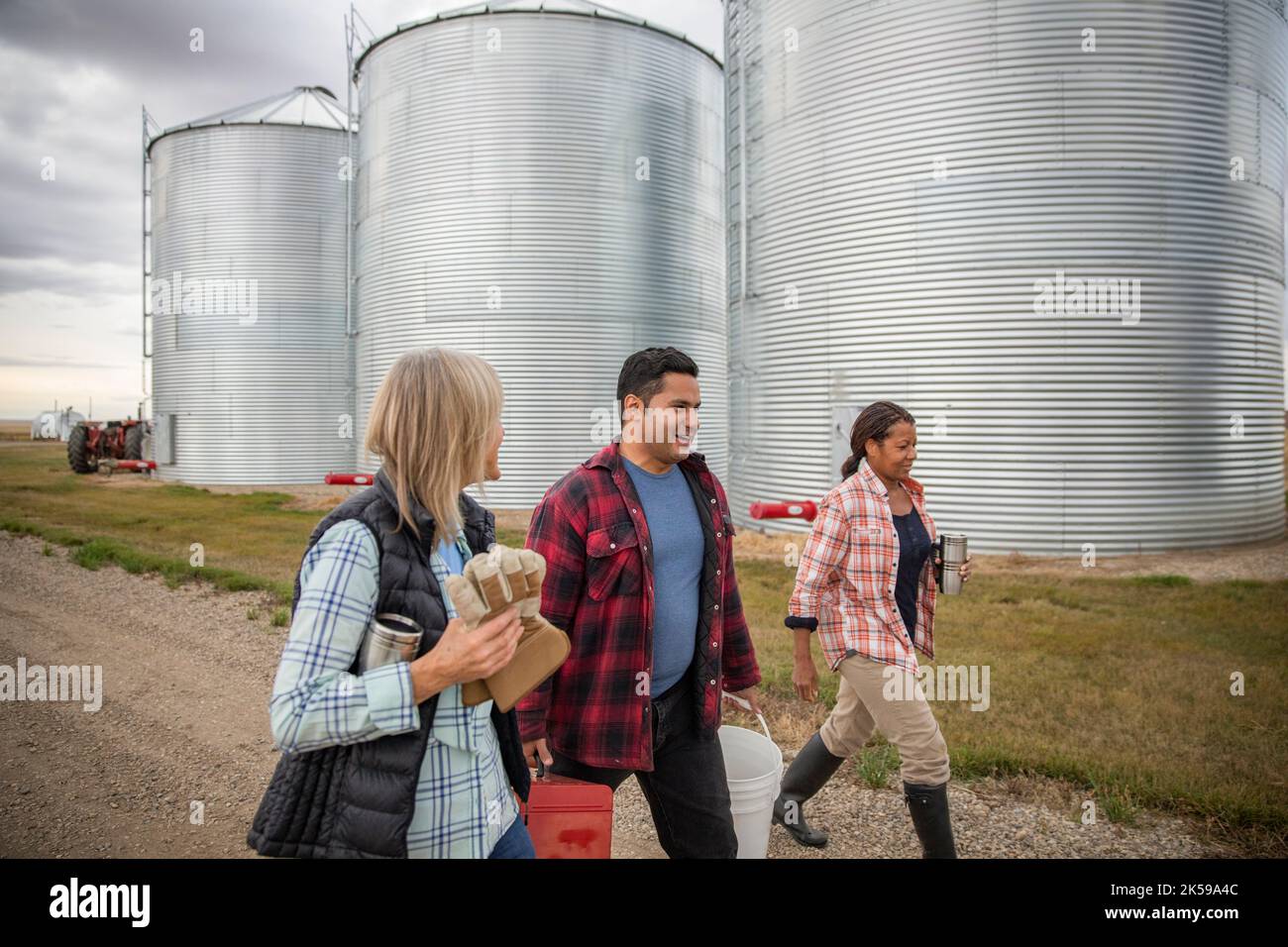 Farmers walking along silos on farm Stock Photo Alamy