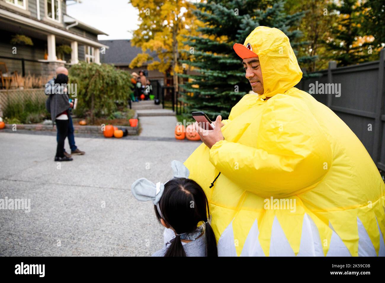 Parents chaperoning children trick or treating on Halloween Stock Photo