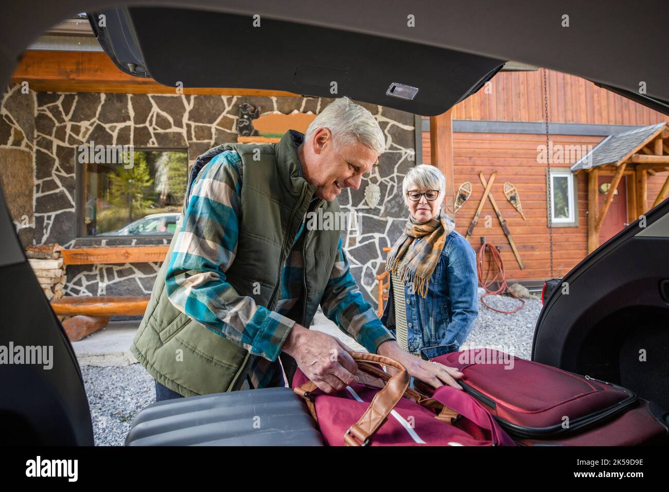 Senior couple arriving at hotel lodge, unloading luggage from car Stock