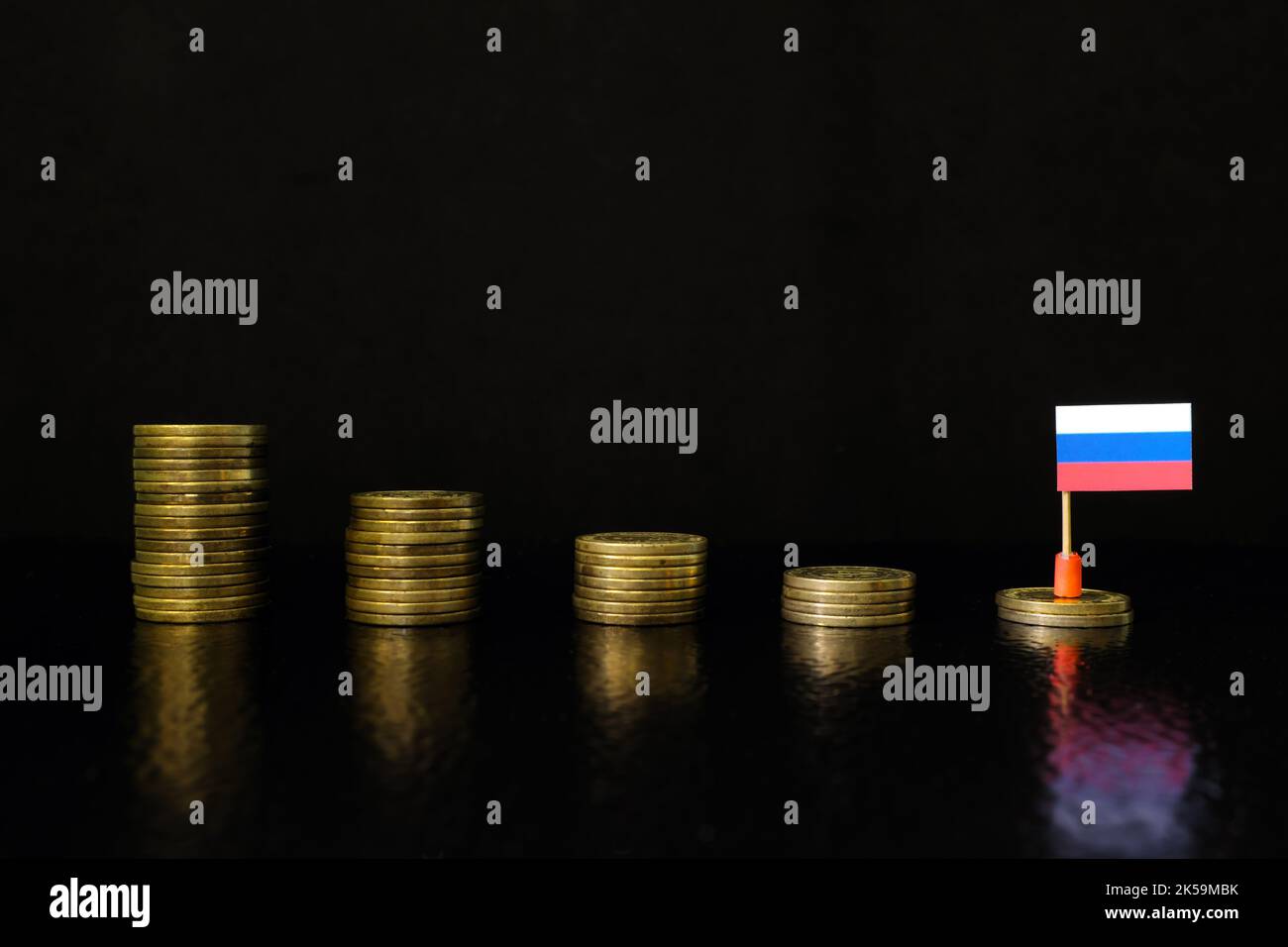 Russia economic recession, financial crisis and currency depreciation concept. Russian flag in decreasing stack of coins in dark black background. Stock Photo