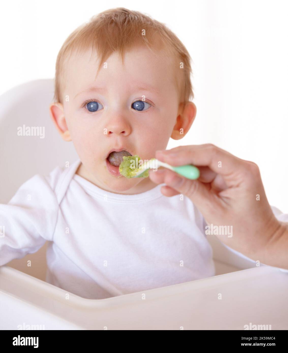 Lets give it a try. A cute baby receiving a spoonful of food from his ...