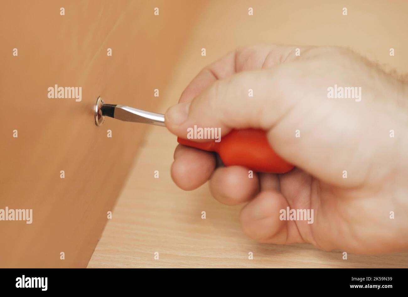 A man disassembles furniture at home with his own hands. Close-up. Stock Photo