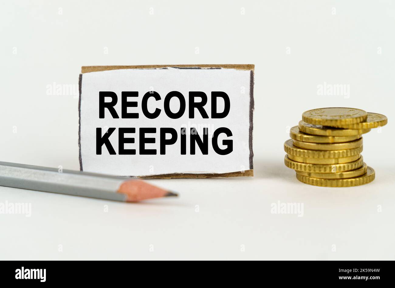 Business concept. On a white background, a pencil, coins and a sign with the inscription - Record keeping Stock Photo