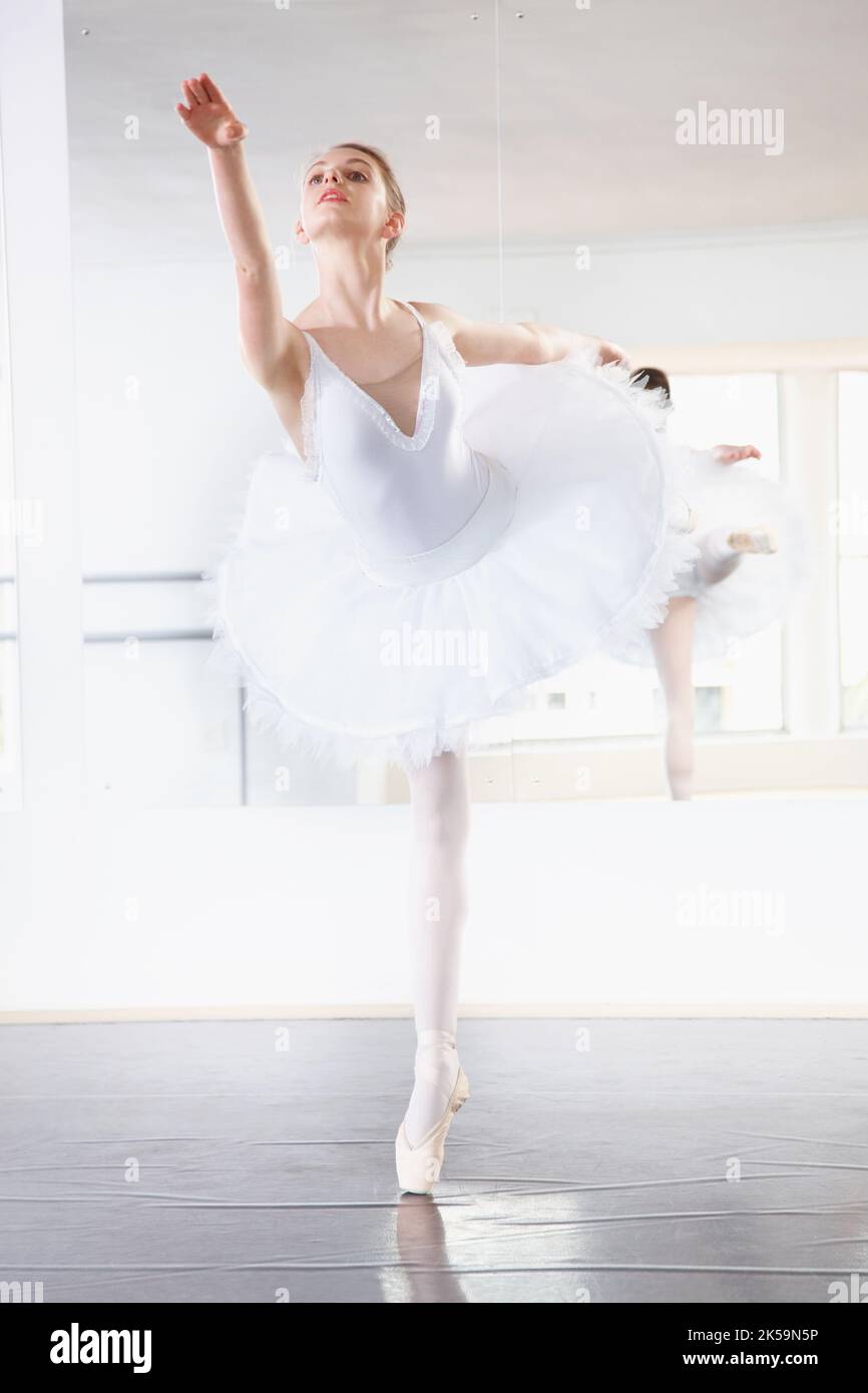 Statuesque ballerina. Full length shot of a ballerina rehearsing in a studio with a mirror behind her. Stock Photo