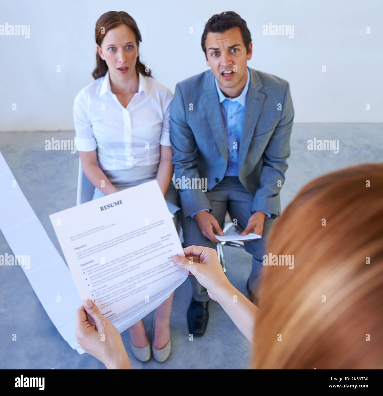 Too qualified. Two employers astounded by the long resume a candidate has brought in to an interview. Stock Photo